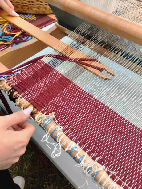 Close-up of hands tying knots on a loom.