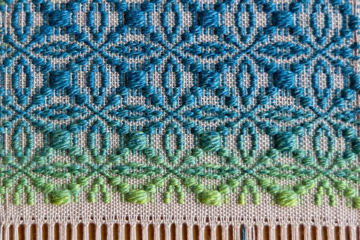 An overhead shot of a large weaving loom with a complex pattern in progress.